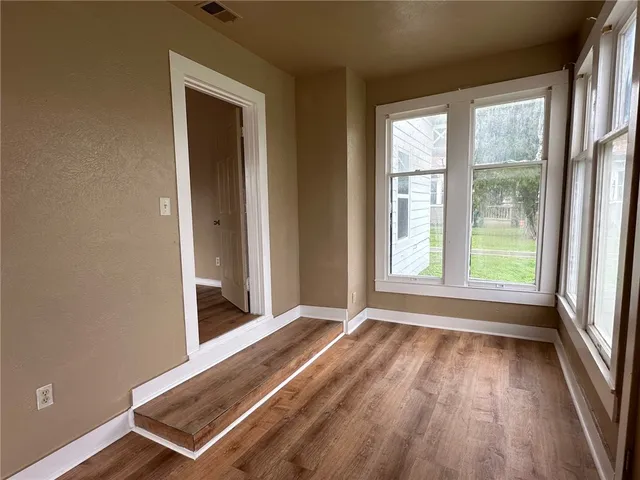 an empty room with wooden floor and windows