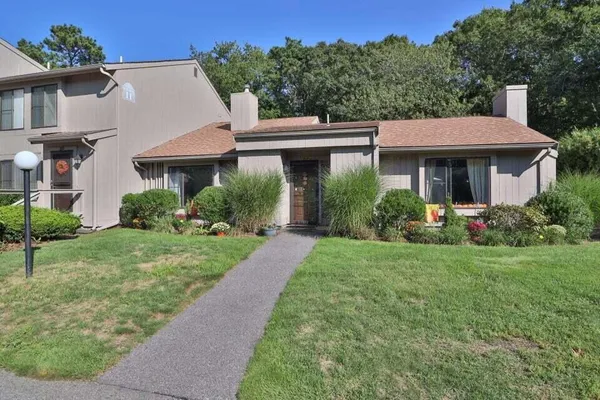a view of a house with brick walls and a yard with plants