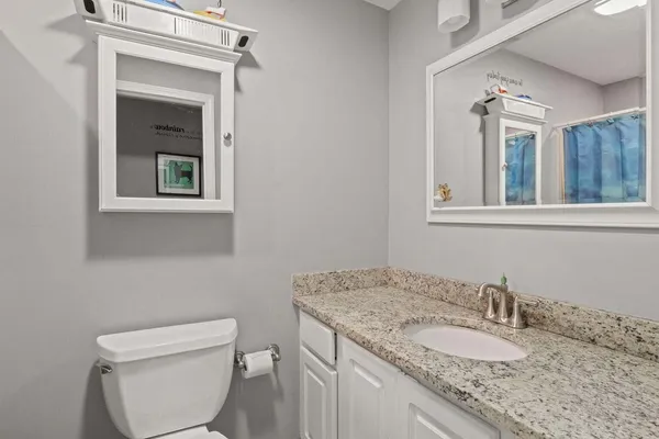 a bathroom with a granite countertop sink toilet and mirror