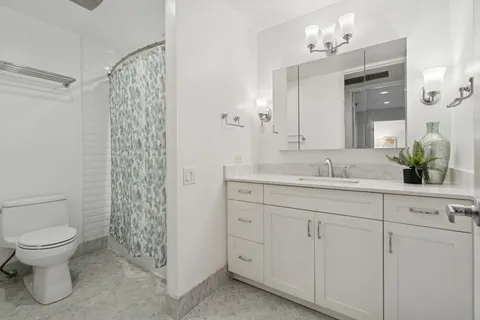 a bathroom with a granite countertop sink a toilet and a mirror