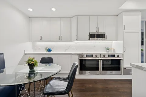 a kitchen with stainless steel appliances a dining table chairs and stove