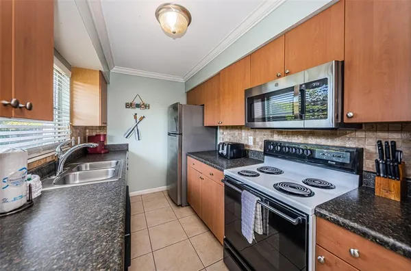 a kitchen with granite countertop a sink a stove and cabinets