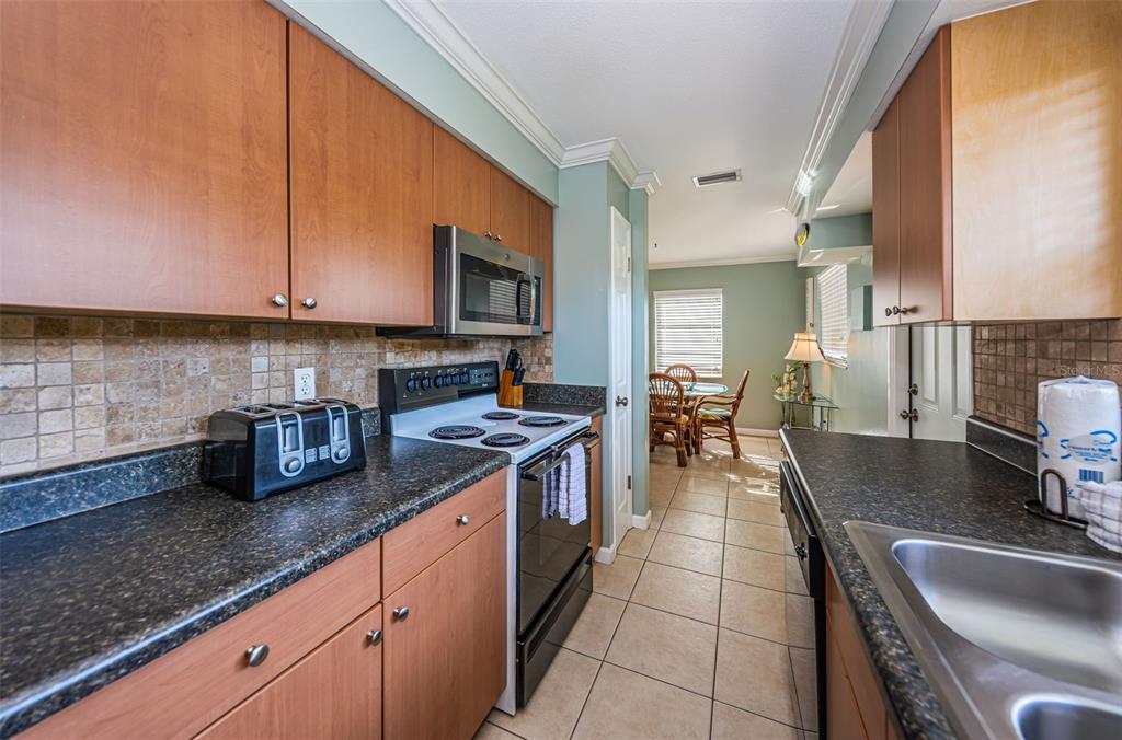6020 Midnight Pass Road, Unit 14A Sarasota, FL 34242 - Photo 12 of 18 a kitchen with granite countertop a sink a stove and cabinets