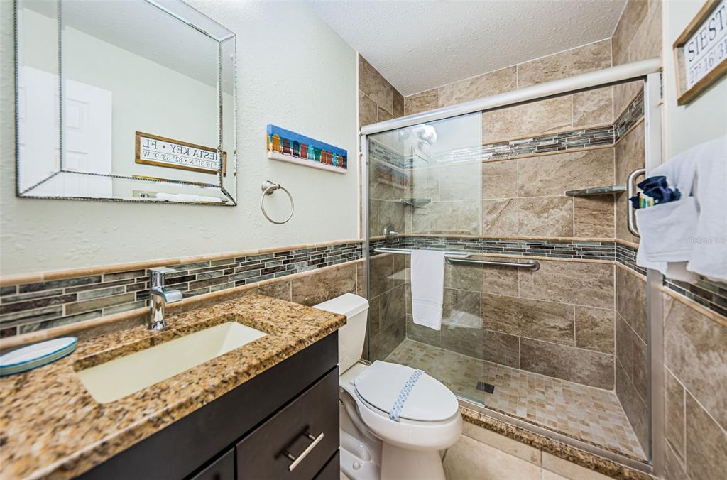 6020 Midnight Pass Road, Unit 14A Sarasota, FL 34242 - Photo 15 of 18 a bathroom with a granite countertop sink a mirror and a shower