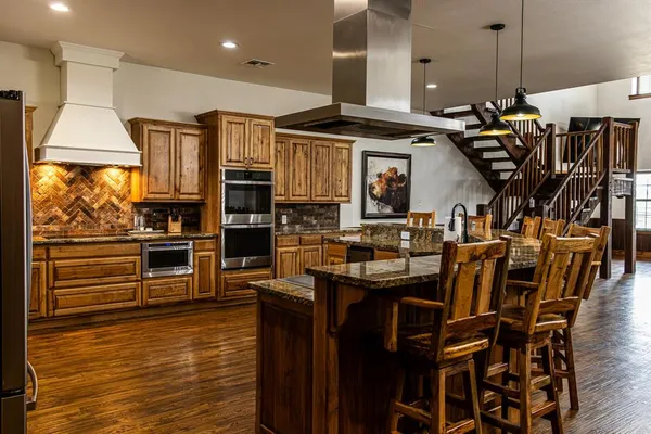 a kitchen with stainless steel appliances kitchen island granite countertop a stove a sink and a microwave