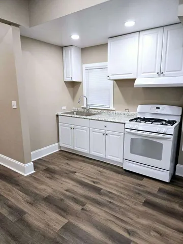 a kitchen with stainless steel appliances granite countertop a stove a sink and white cabinets