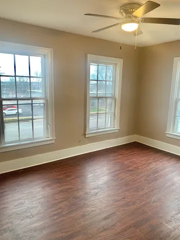 an empty room with wooden floor and windows