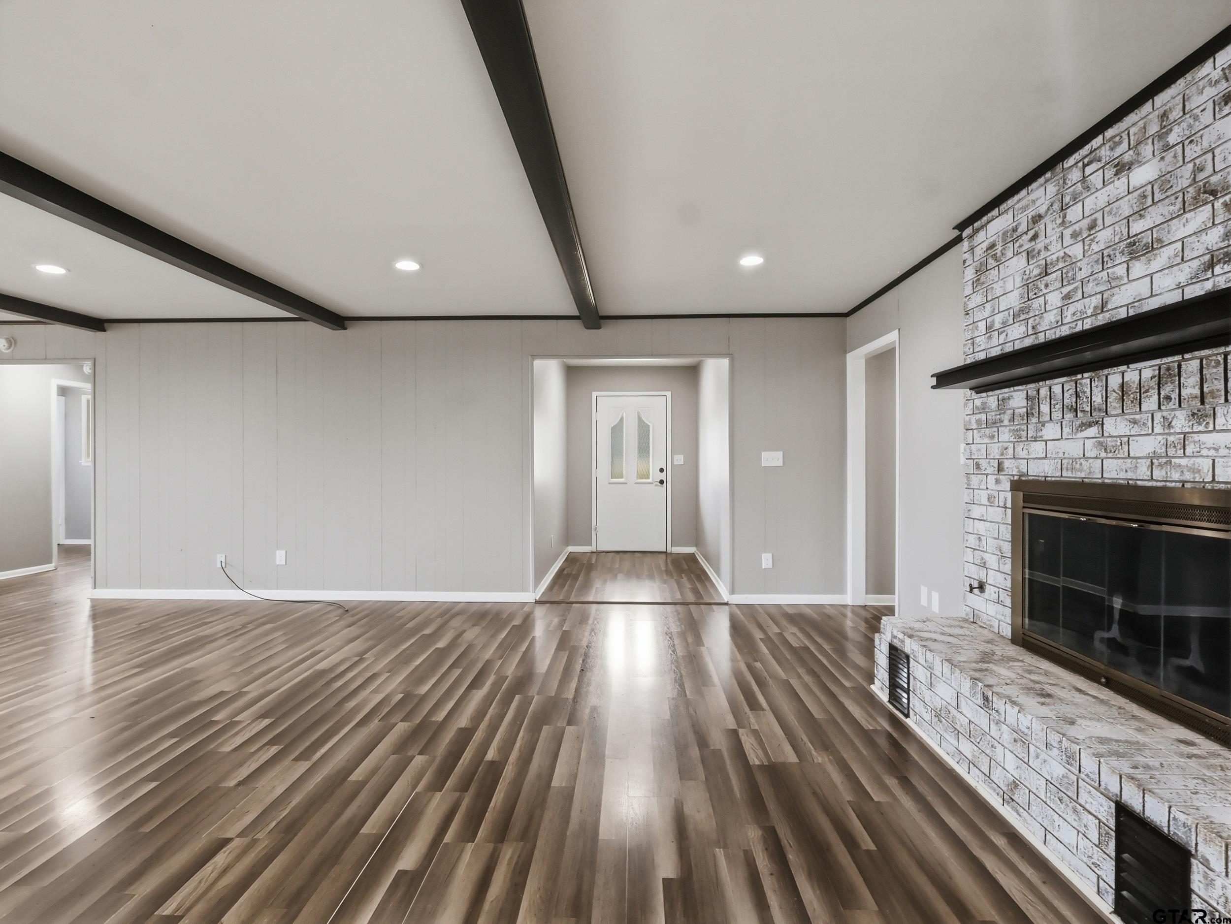a view of an empty room with wooden floor fireplace and a window