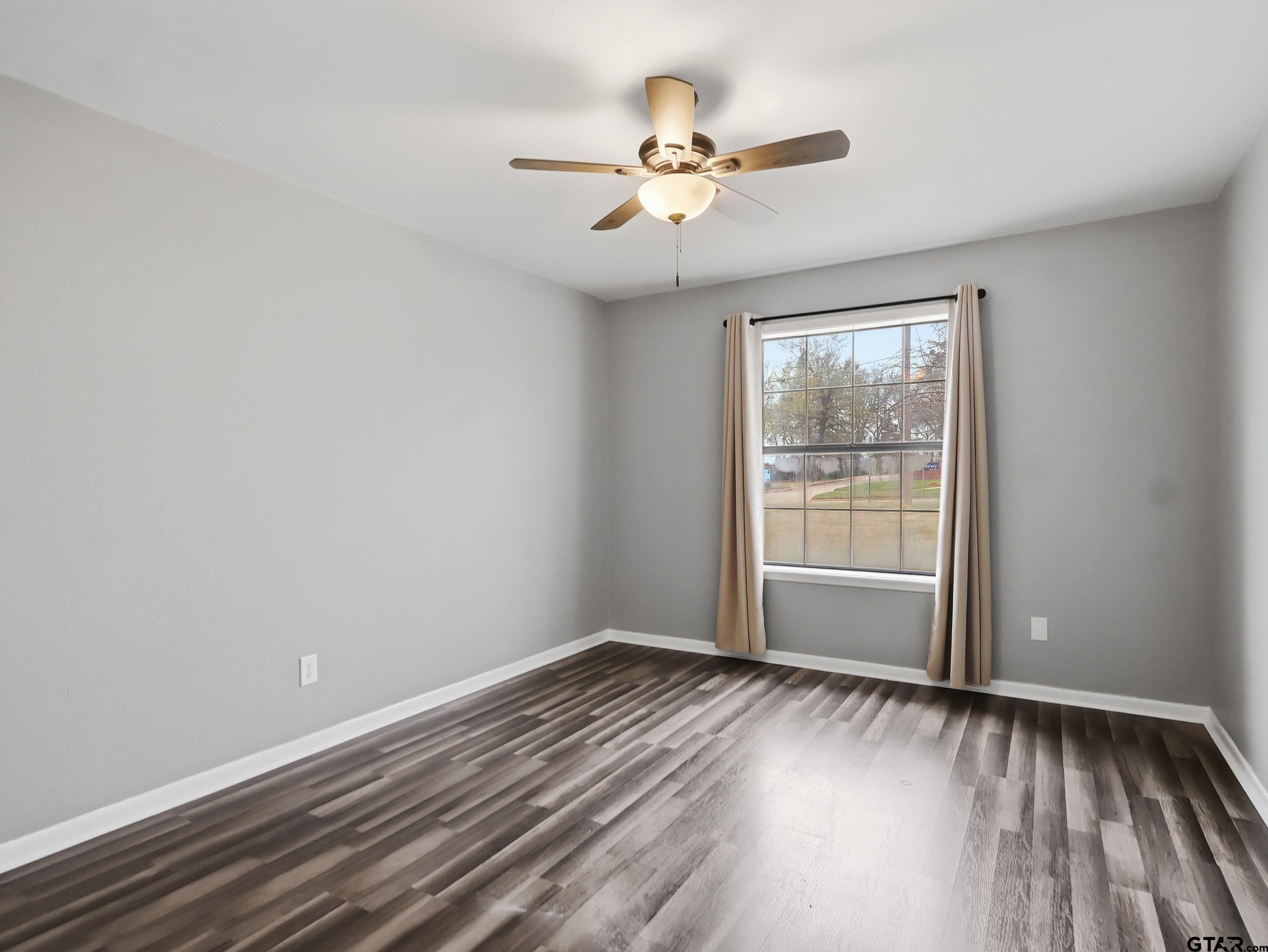 231 Quitman Street Pittsburg, TX 75686 - Photo 17 of 31 wooden floor in an empty room with a window