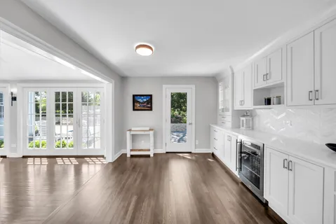 a open kitchen with granite countertop a stove top oven a sink and white cabinets with wooden floor