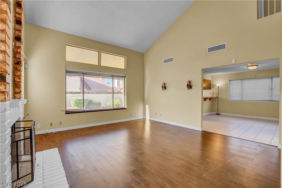 6440 Hartwood Road Las Vegas, NV 89108 - Photo 5 of 59 A striking fireplace and vaulted ceilings define this sun-filled living space with rich hardwood flooring.