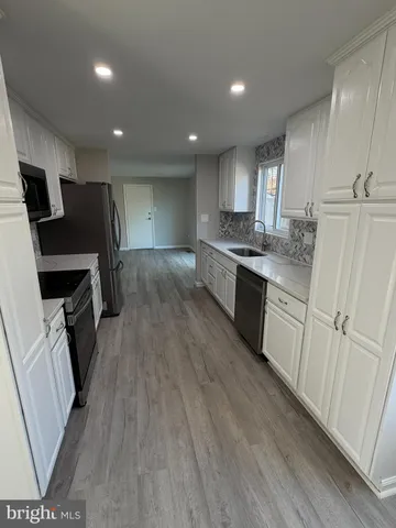 a kitchen with granite countertop a sink a counter top space stainless steel appliances and cabinets