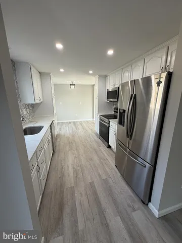 a kitchen with granite countertop a refrigerator stove and wooden floor
