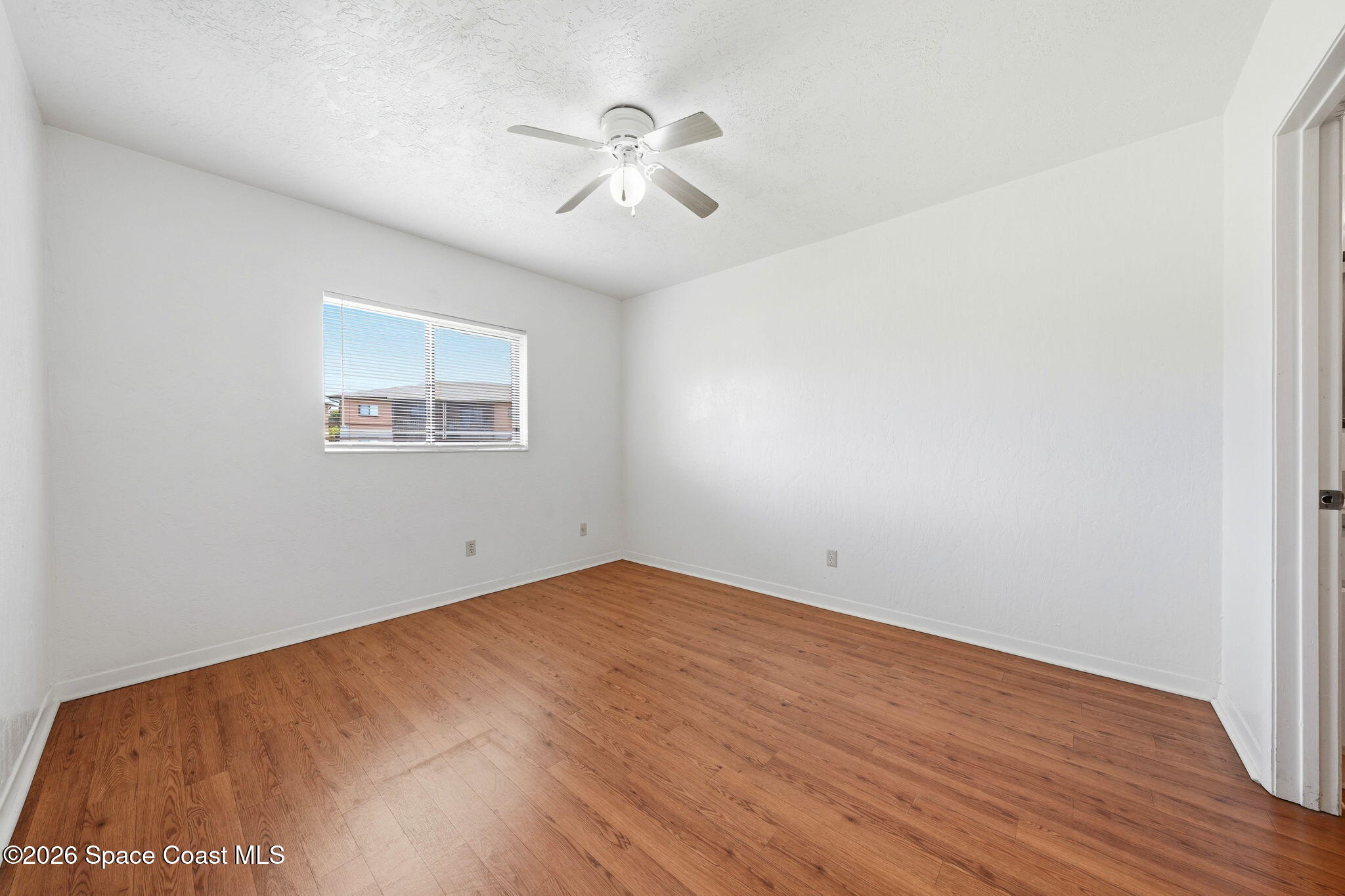 1702 University Lane, Unit 804 Cocoa, FL 32922 - Photo 16 of 25 an empty room with wooden floor chandelier fan and windows