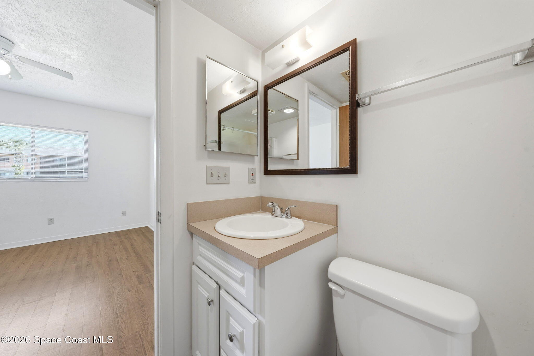 1702 University Lane, Unit 804 Cocoa, FL 32922 - Photo 19 of 25 a bathroom with a toilet sink vanity and mirror