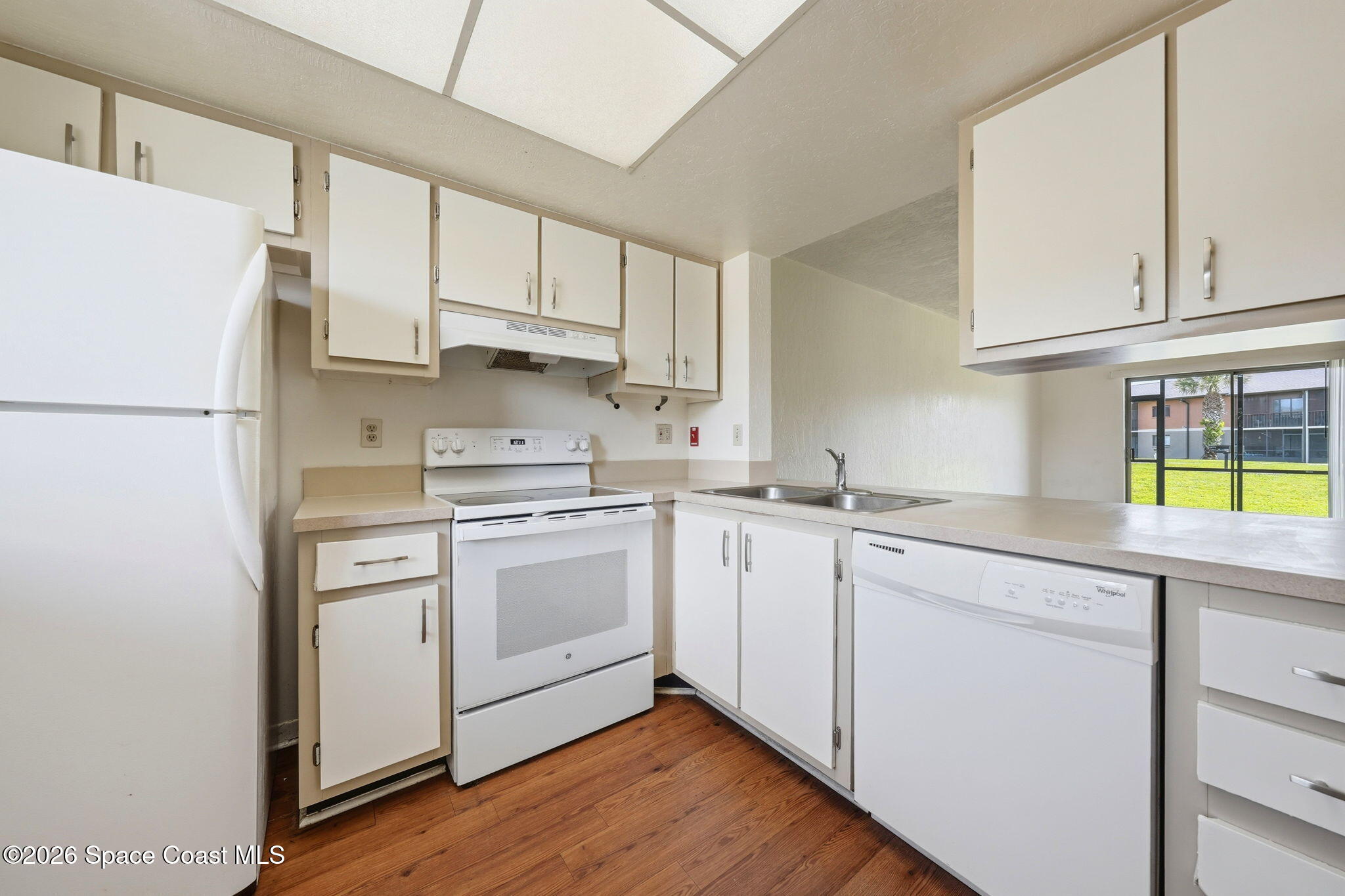 1702 University Lane, Unit 804 Cocoa, FL 32922 - Photo 4 of 25 a kitchen with stainless steel appliances granite countertop a sink a stove a refrigerator and white cabinets with wooden floor
