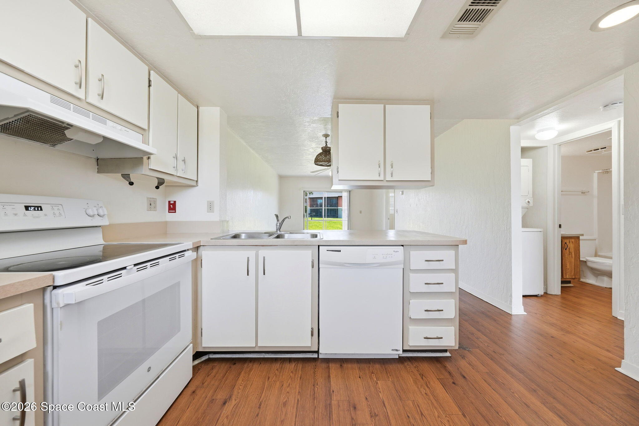 1702 University Lane, Unit 804 Cocoa, FL 32922 - Photo 7 of 25 a kitchen with wooden floors and white appliances