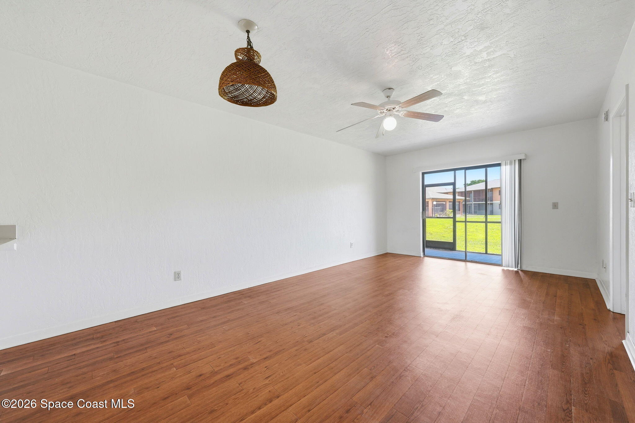 1702 University Lane, Unit 804 Cocoa, FL 32922 - Photo 8 of 25 a view of empty room with wooden floor and fan