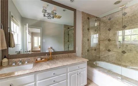 a bathroom with a granite countertop sink mirror and shower