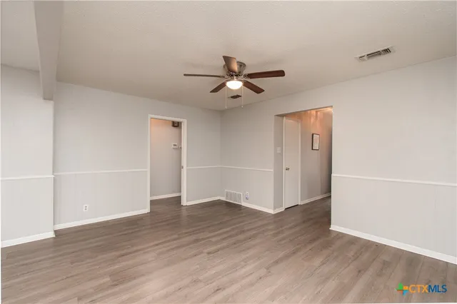 an empty room with wooden floor and ceiling fan