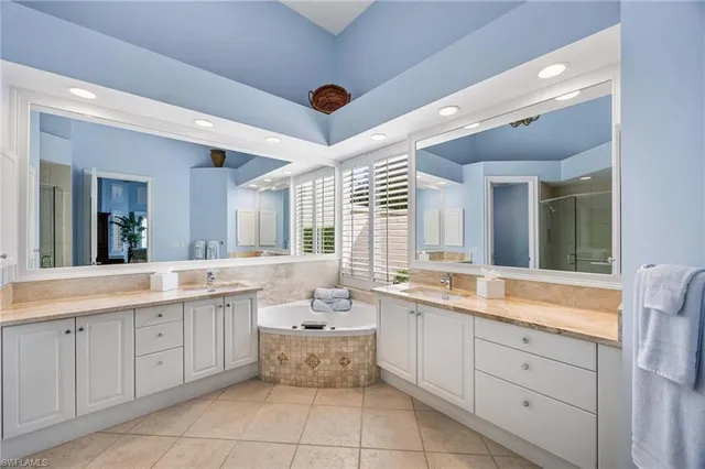a large white bathroom with a sink mirror and a bathtub