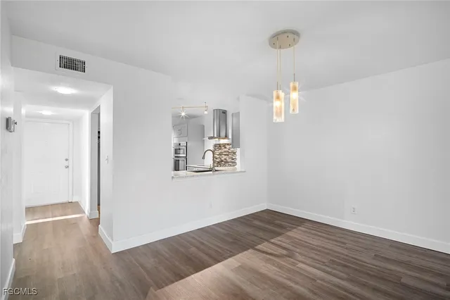 a view of a hallway with wooden floor and a chandelier