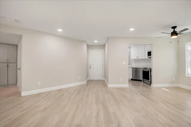 an empty room with wooden floor fireplace and windows