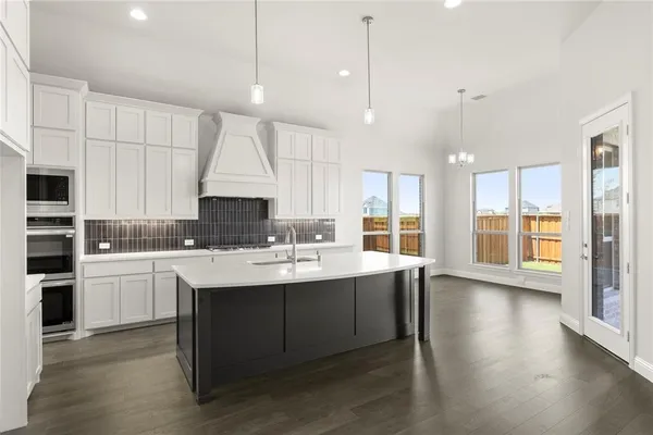 a kitchen with stainless steel appliances granite countertop a sink a stove and a refrigerator