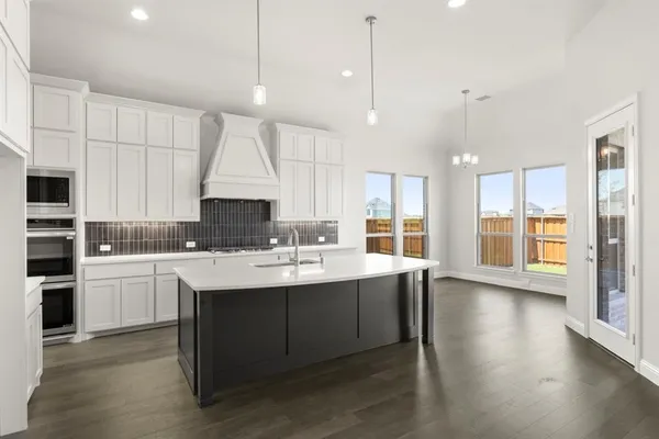 a kitchen with stainless steel appliances granite countertop a sink a stove and a wooden floor