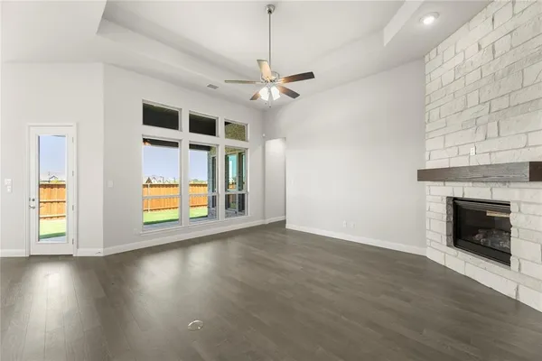 an empty room with wooden floor fireplace and windows