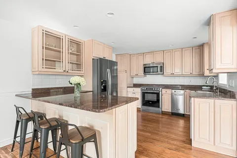 a living room with stainless steel appliances granite countertop a couch and a view of kitchen