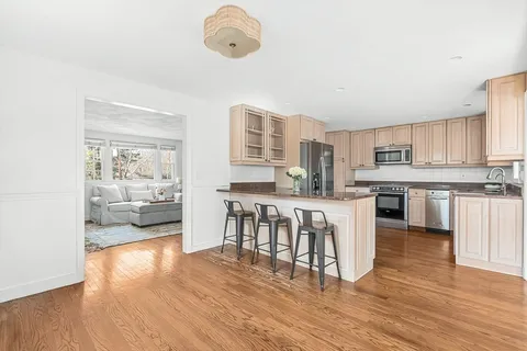 a kitchen with kitchen island granite countertop a stove top oven a sink a dining table and chairs