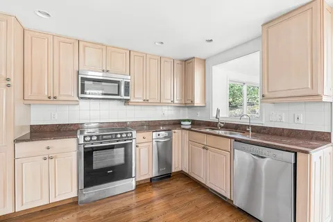 a kitchen with cabinets stainless steel appliances a sink and a window