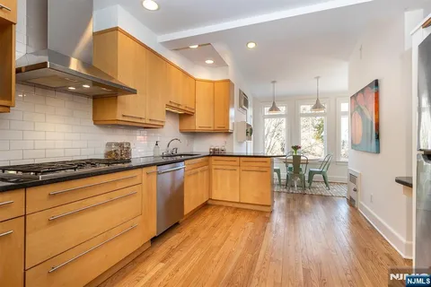 a kitchen with stainless steel appliances granite countertop wooden floors stove top oven and sink