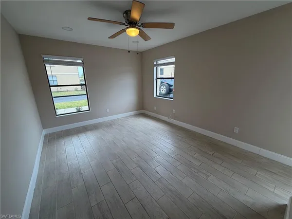 an empty room with wooden floor and a ceiling fan