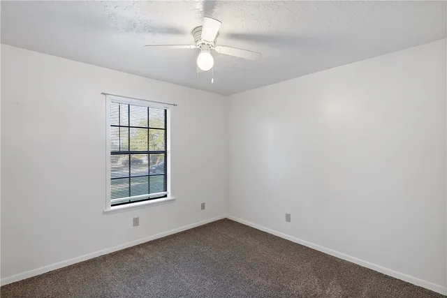 an empty room with windows and ceiling fan
