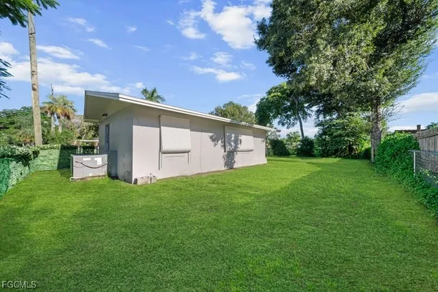 a backyard of a house with plants and large tree