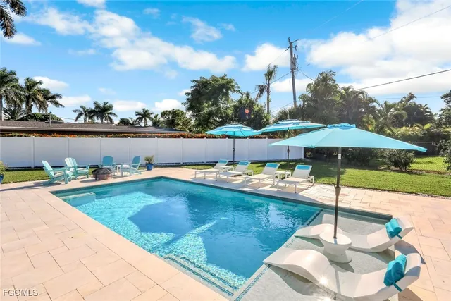 a view of a swimming pool with a table and chairs under an umbrella