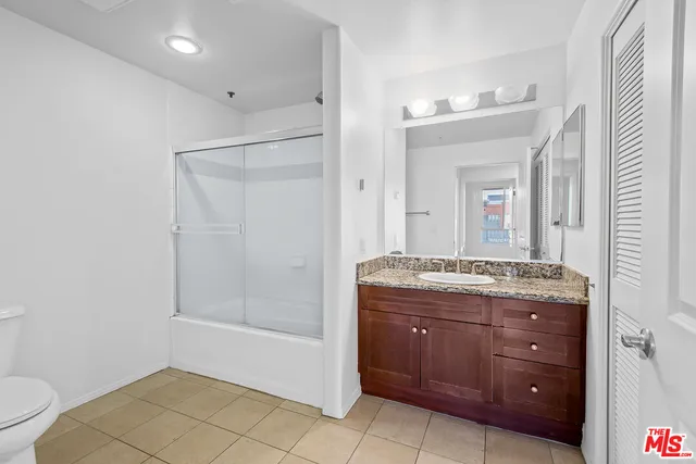 a bathroom with a granite countertop sink a mirror and a toilet