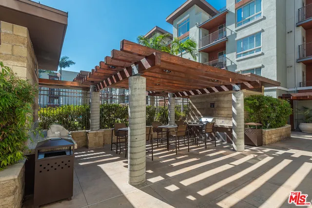 a dining area with stainless steel appliances kitchen island granite countertop a dining table chairs and a refrigerator