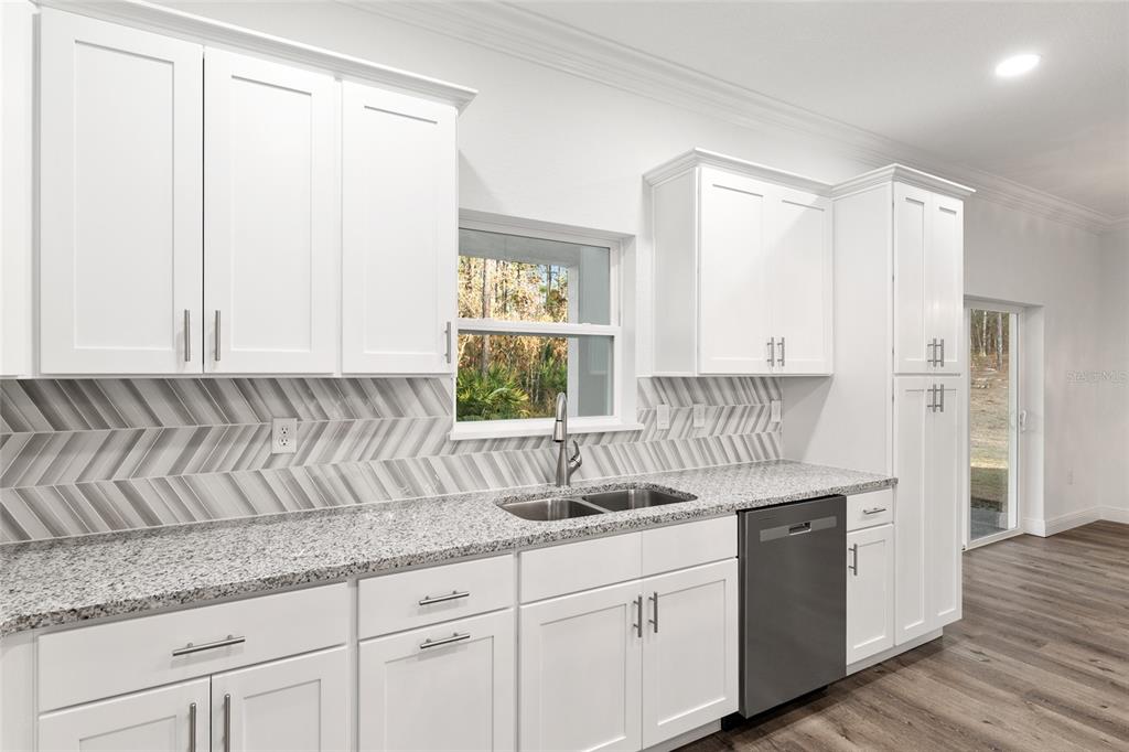 8725 Southwest 136th Terrace Dunnellon, FL 34432 - Photo 30 of 78 a kitchen with granite countertop white cabinets and sink