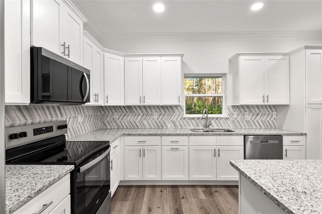 8725 Southwest 136th Terrace Dunnellon, FL 34432 - Photo 31 of 78 a kitchen with granite countertop a sink a stove and cabinets