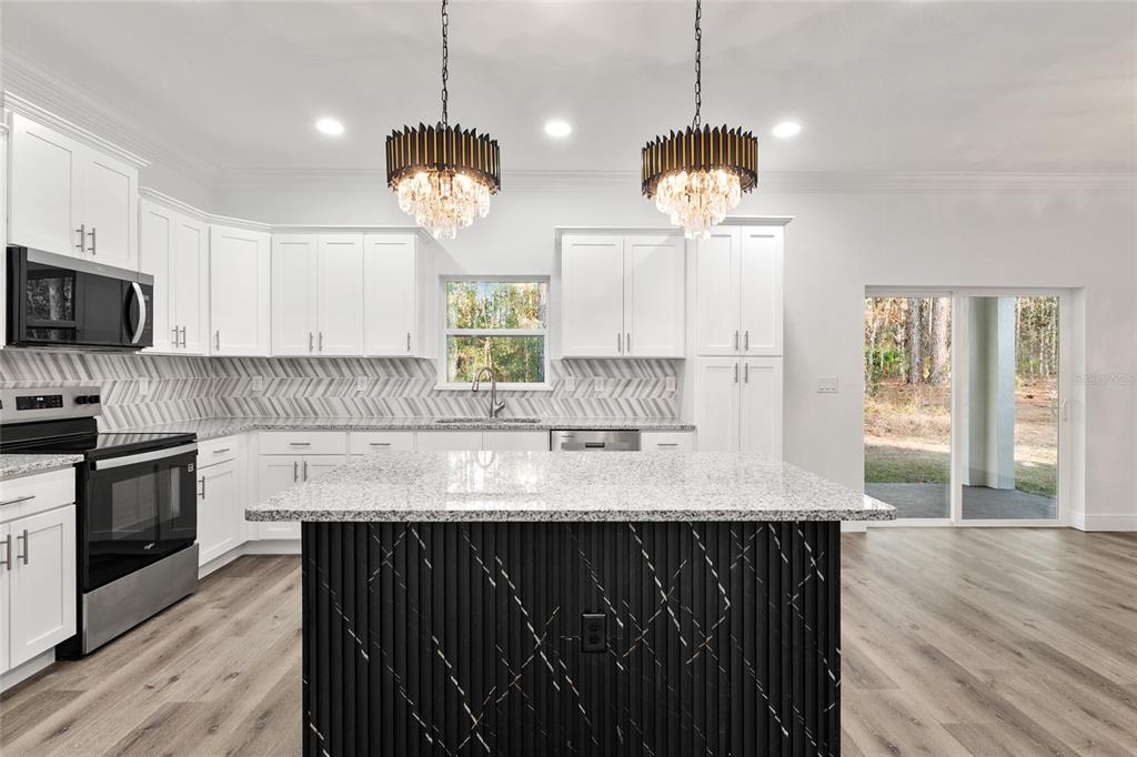 8725 Southwest 136th Terrace Dunnellon, FL 34432 - Photo 32 of 78 a kitchen with kitchen island granite countertop a stove a sink and a wooden floor