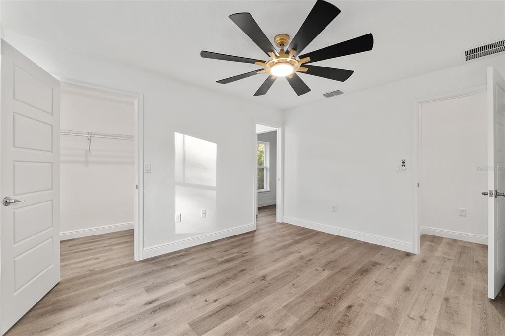 8725 Southwest 136th Terrace Dunnellon, FL 34432 - Photo 57 of 78 an empty room with wooden floor chandelier fan and windows