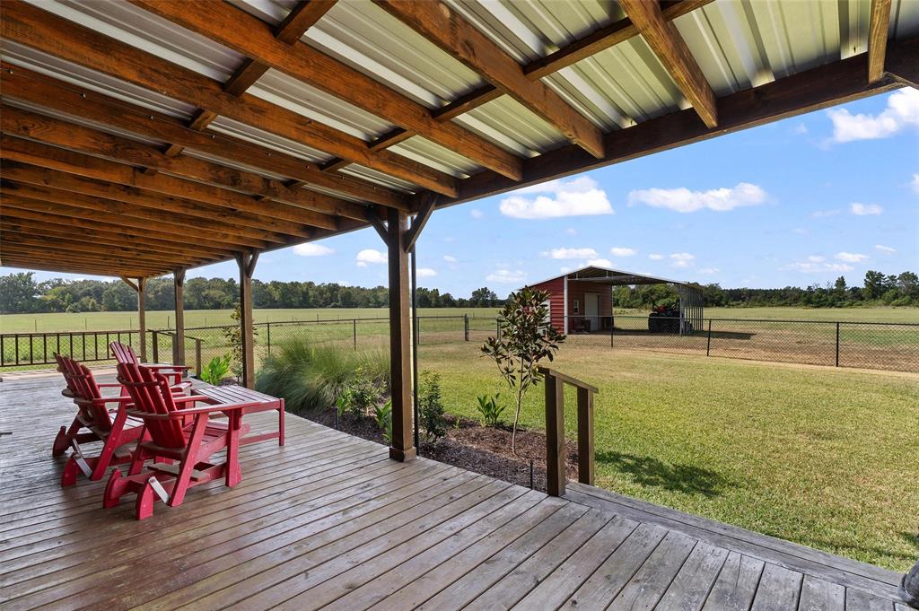 1131 Speights Road Keatchie, LA 71046 - Photo 31 of 33 Expansive wooden deck with an exposed beam ceiling and metal roof, overlooking a fenced green space