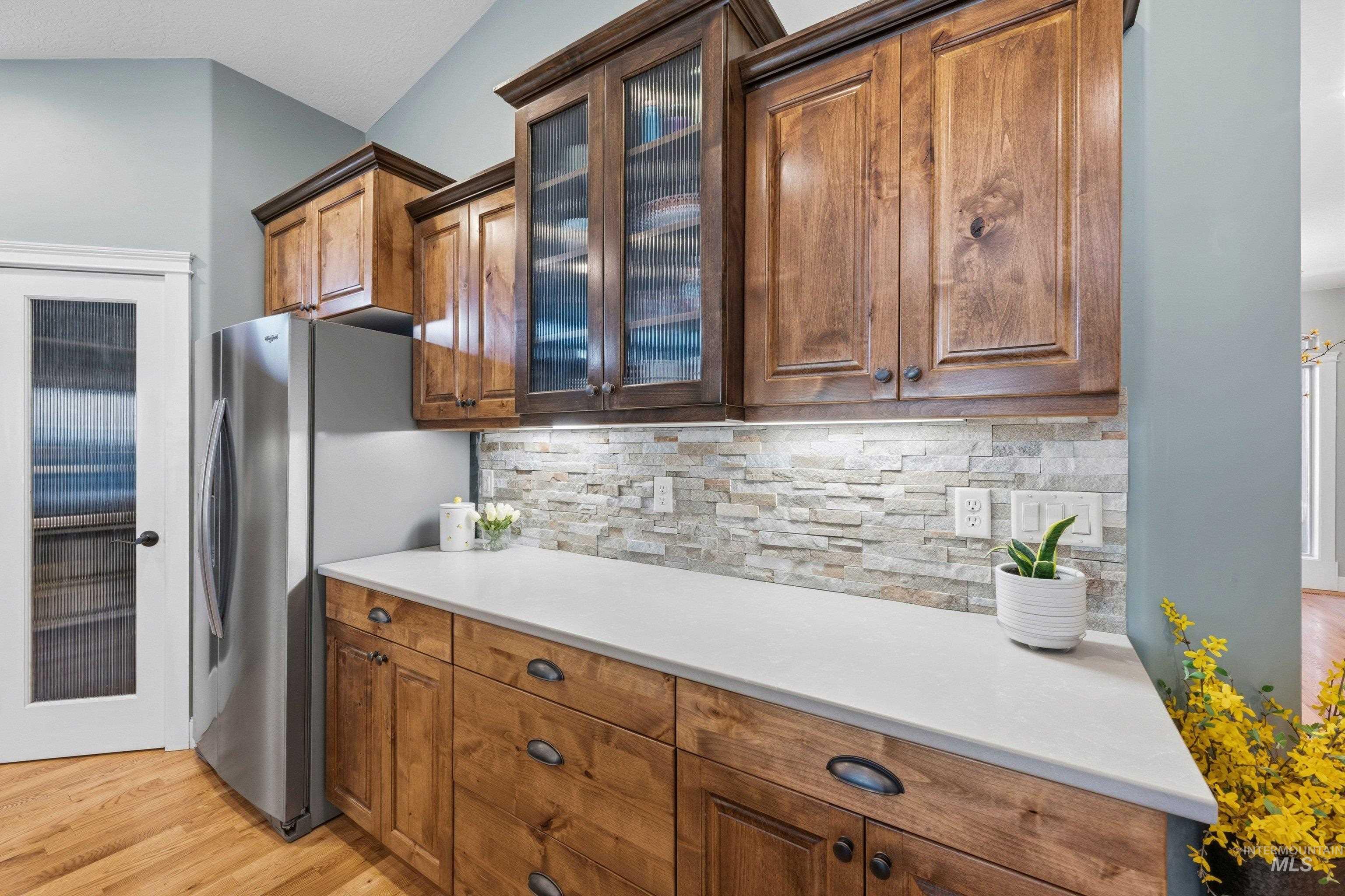 5850 North Rio Lomas Avenue Meridian, ID 83646 - Photo 13 of 50 Kitchen with glass insert cabinets, freestanding refrigerator, decorative backsplash, wood finish cabinets, and light wood-style flooring