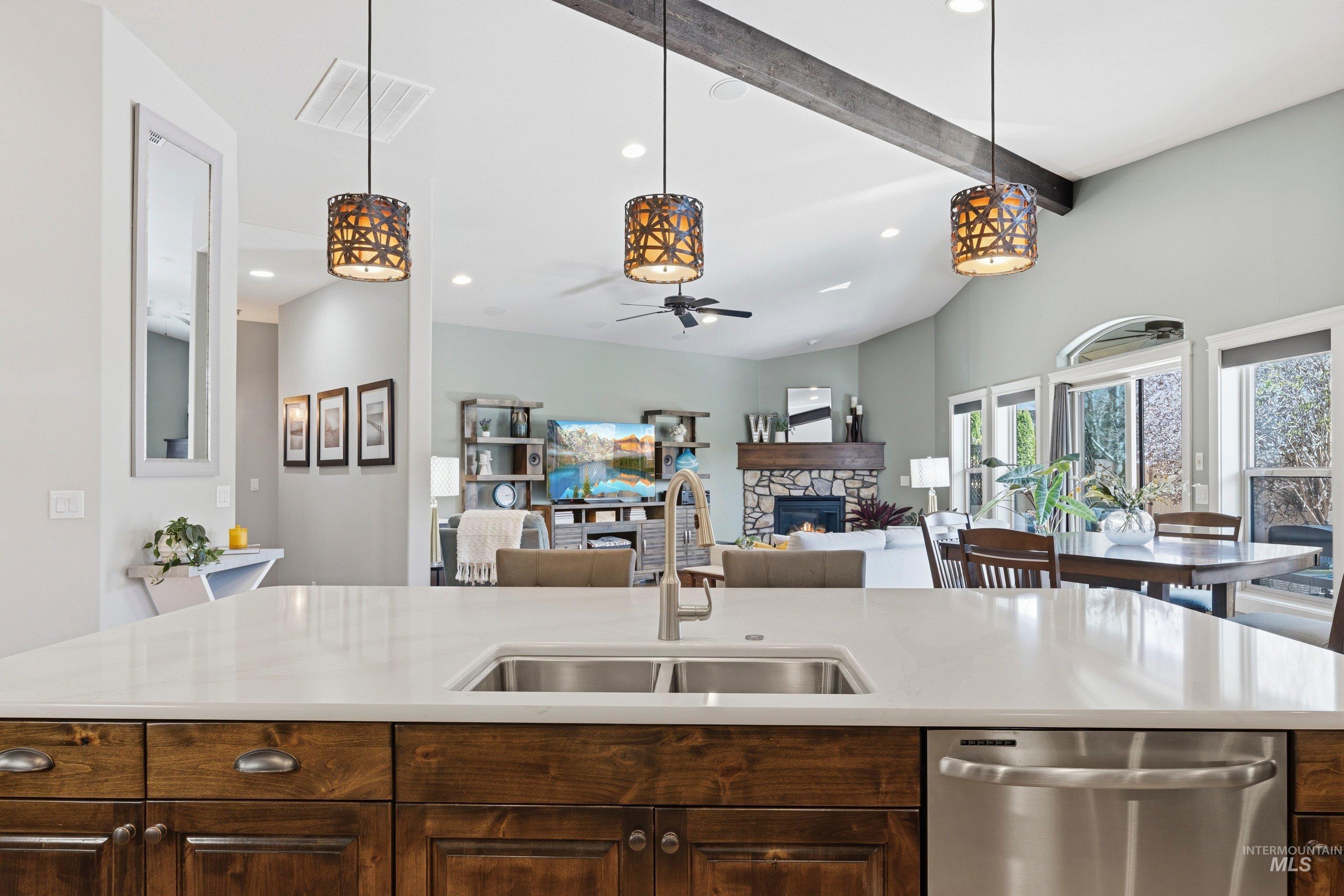 5850 North Rio Lomas Avenue Meridian, ID 83646 - Photo 49 of 50 Kitchen featuring dark wood finish cabinets, a fireplace, stainless steel dishwasher, open floor plan, and pendant lighting