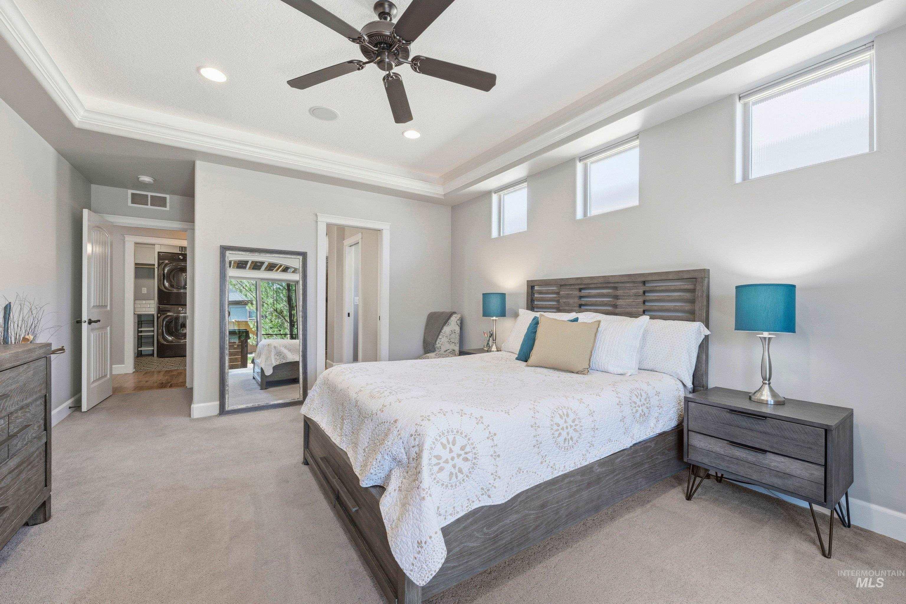 5850 North Rio Lomas Avenue Meridian, ID 83646 - Photo 22 of 50 Bedroom featuring light colored carpet, a tray ceiling, a ceiling fan, stacked washer and dryer, and recessed lighting
