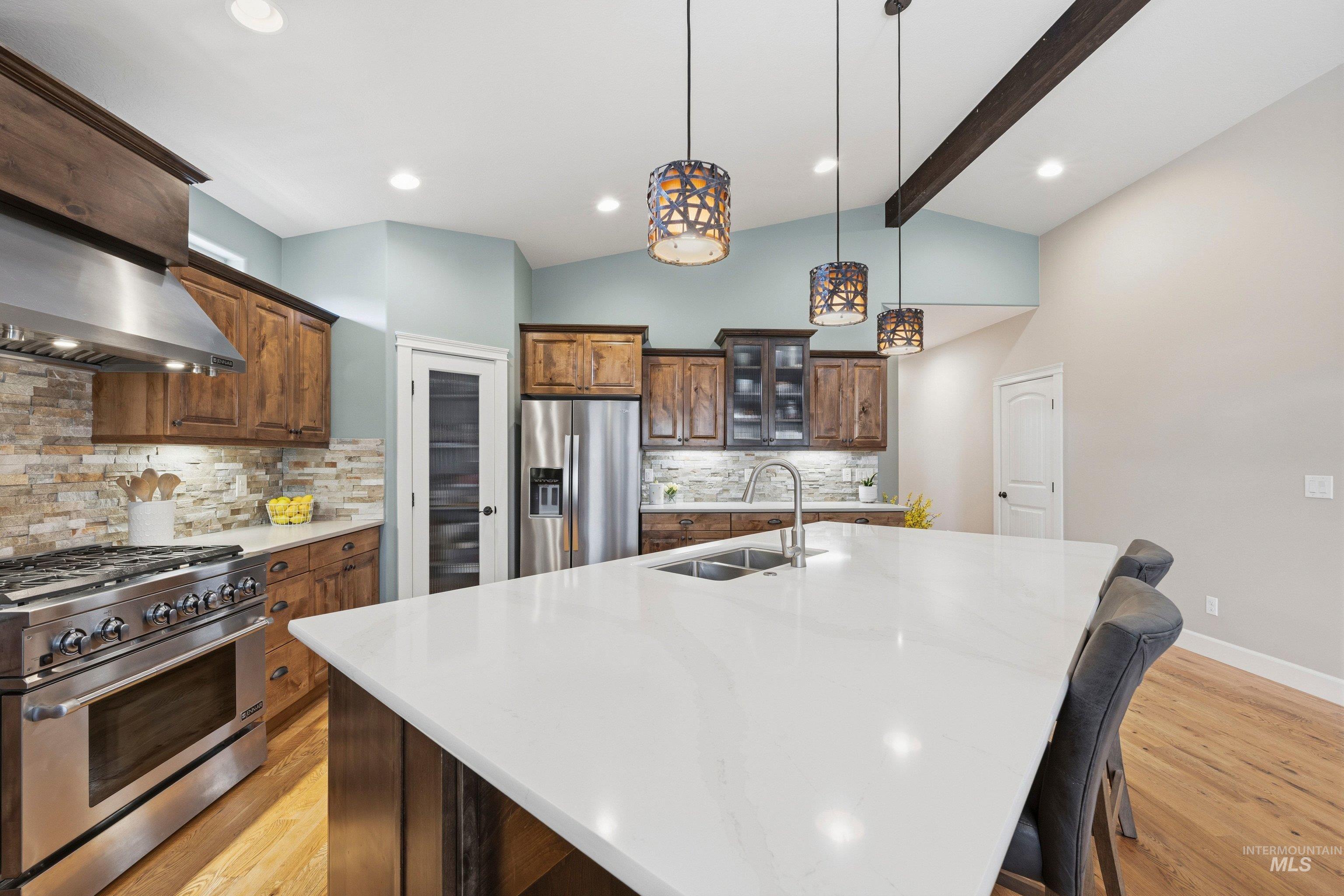 5850 North Rio Lomas Avenue Meridian, ID 83646 - Photo 8 of 50 Kitchen featuring stainless steel appliances, light wood-style flooring, light stone countertops, glass insert cabinets, and lofted ceiling with beams