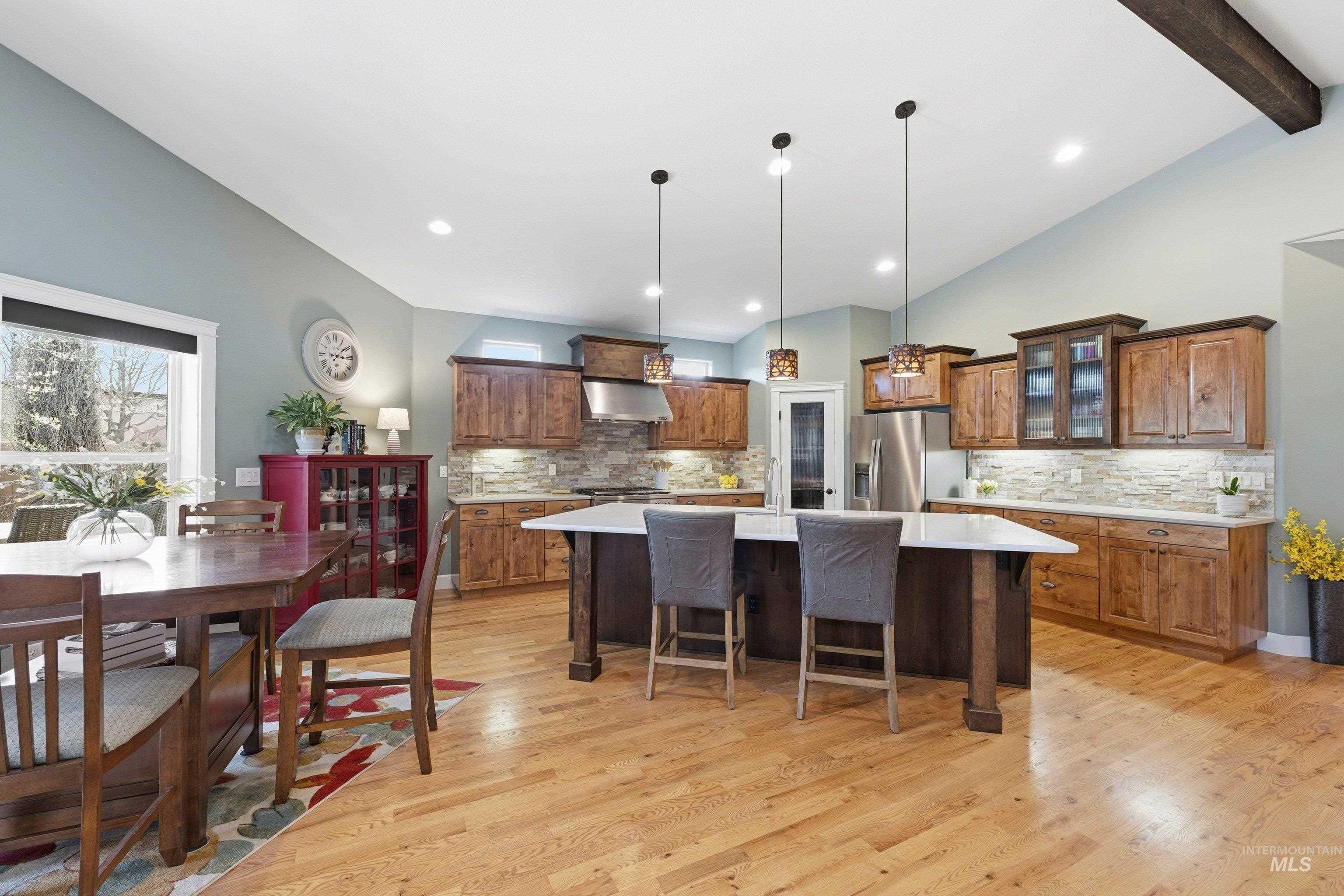 5850 North Rio Lomas Avenue Meridian, ID 83646 - Photo 10 of 50 Kitchen featuring lofted ceiling with beams, a kitchen island with sink, decorative light fixtures, a breakfast bar, and glass fronted cabinets